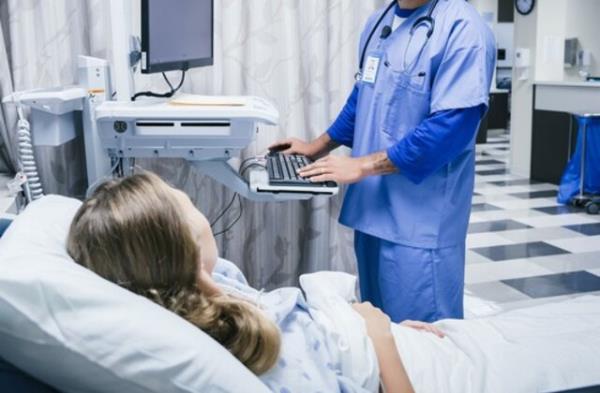 Nurse talking to patient in hospital bed - stock photo
